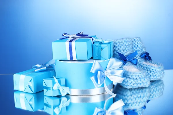Beaux cadeaux et babys bottines sur fond bleu — Photo