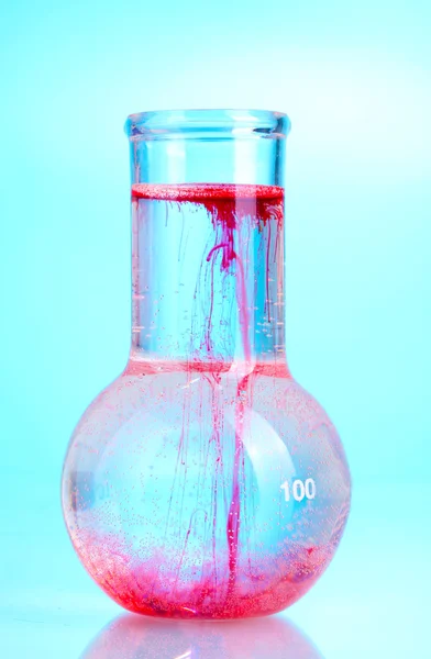 Helle Tinte in einem Kolben mit Wasser auf blauem Hintergrund — Stockfoto