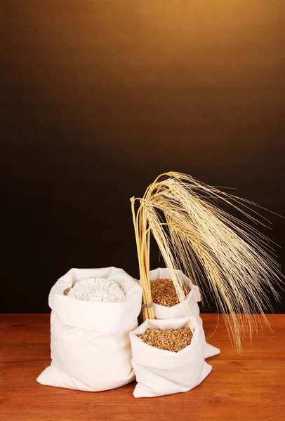 Meel en tarwe graan op houten tafel op donkere achtergrond — Stockfoto