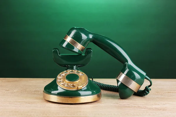 Teléfono retro sobre mesa de madera sobre fondo verde — Foto de Stock