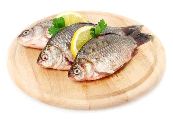 Свежие рыбы с лимоном и петрушкой на деревянной разделочной доске изолированы на белом — стоковое фото