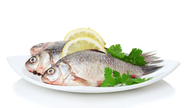Świeże ryby z cytryną i natką pietruszki na płytkę na białym tle — Zdjęcie stockowe