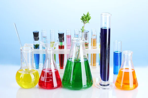 Diferentes cristalería de laboratorio con líquido de color sobre fondo azul — Foto de Stock