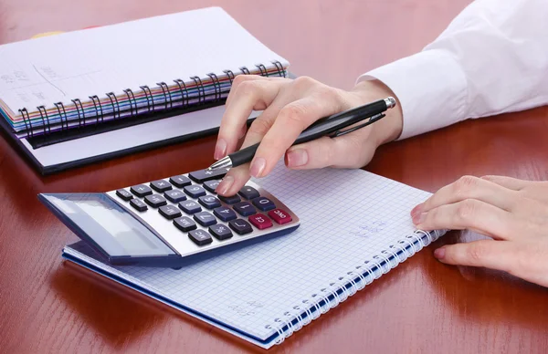 Woman hands with pencil, notebooks and calculator on wooden table — Stock Photo, Image