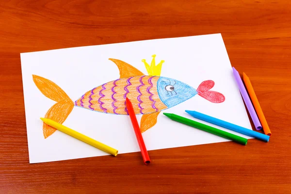 Детский рисунок золотой рыбы и карандашей на деревянном фоне — стоковое фото
