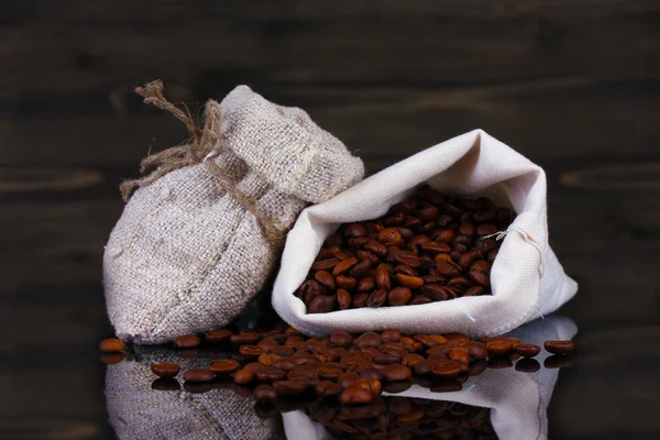 Grãos de café em saco de lona isolado em madeira — Fotografia de Stock
