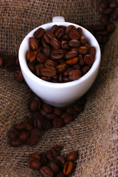Kaffeebohnen in weißer Tasse auf Leinwand Hintergrund — Stockfoto