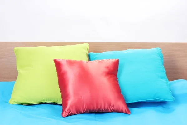Almohadas brillantes en la cama sobre fondo blanco — Foto de Stock