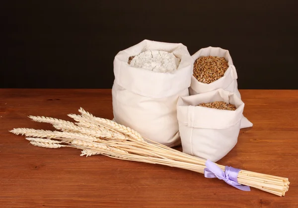 Farina e grano su tavola di legno su fondo scuro — Foto Stock