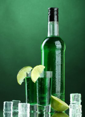 şişe ve bardak pelin yeşil zemin üzerine buz ve limon ile