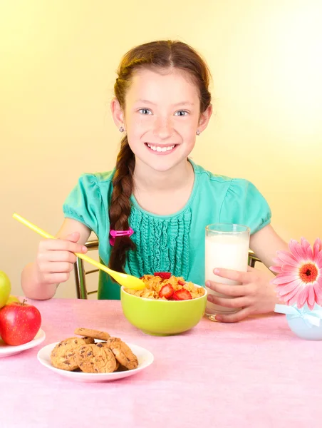 Маленькая красивая девочка завтракает на бежевом фоне — стоковое фото