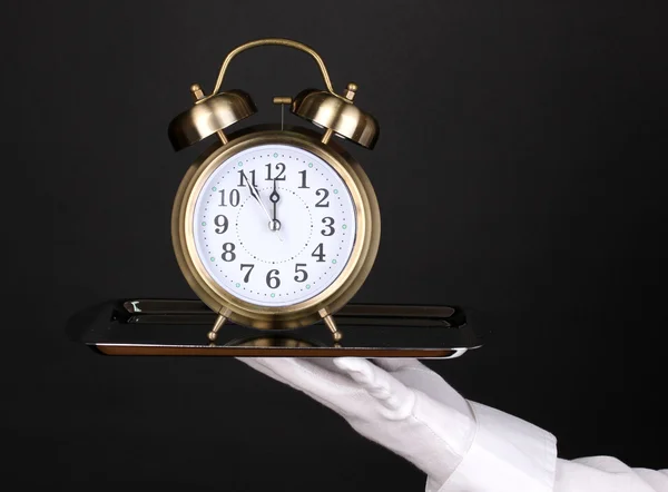 Χέρι-γάντι, κρατώντας το ασημένιο δίσκο με το ρολόι συναγερμών που απομονώνονται σε μαύρο — Φωτογραφία Αρχείου