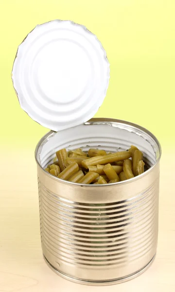 Open tin can of french bean on wooden table on green background — Stock Photo, Image