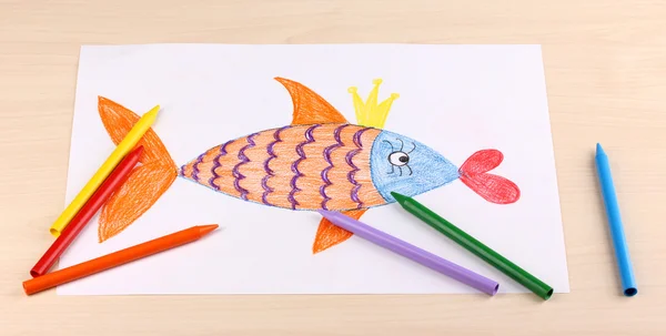 Детский рисунок золотой рыбы и карандашей на деревянном фоне — стоковое фото