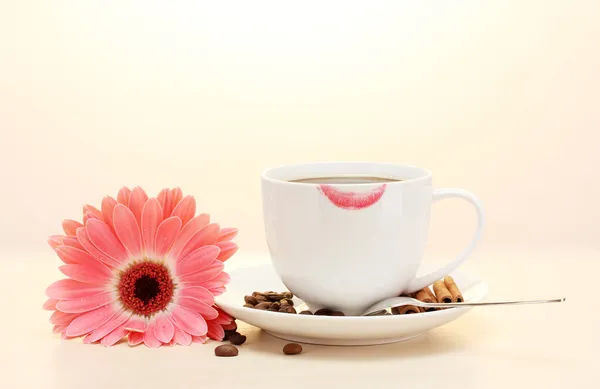 Cup of coffee with lipstick mark and gerbera beans, cinnamon sticks on wooden table — Stock Photo, Image