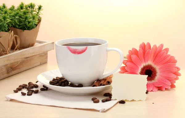 Xícara de café com marca de batom e feijão gerbera, paus de canela na mesa de madeira — Fotografia de Stock