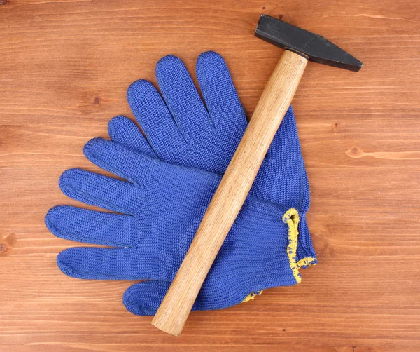 Martillo y guantes sobre fondo de madera — Foto de Stock