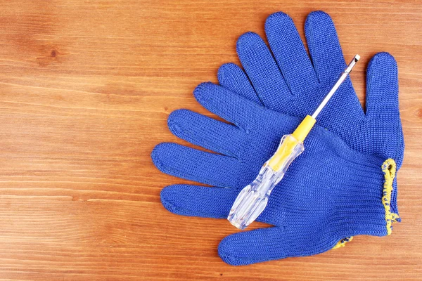 stock image Screwdriver and gloves on wooden background