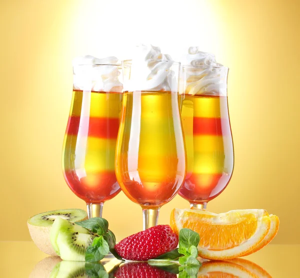 Gelatina de frutas en vasos y frutas sobre fondo amarillo — Foto de Stock