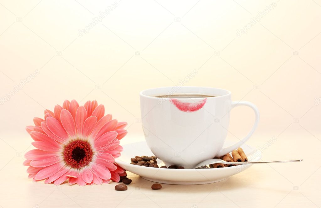 Cup of coffee with lipstick mark and gerbera beans, cinnamon sticks on wooden table