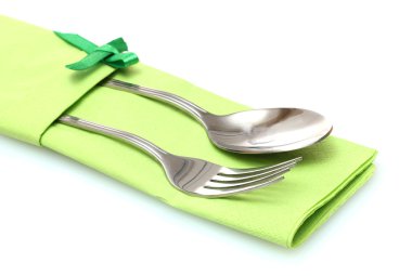 Fork and spoon in a green cloth with a bow isolated on white