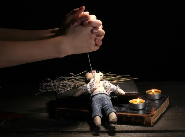 ブードゥー教の人形の少年が木製のテーブル、ろうそくの光で針穴を開けて — ストック写真