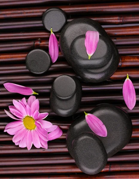 Piedras de spa y flores en estera de bambú — Foto de Stock