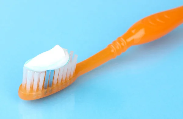 Zahnbürste mit Paste auf blauem Hintergrund — Stockfoto