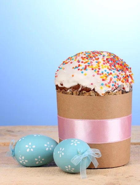 Krásné velikonoční dort se vejce na dřevěný stůl na modrém pozadí — Stock fotografie
