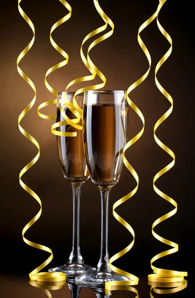 Glasses of champagne and streamer on brown background — Stock Photo, Image