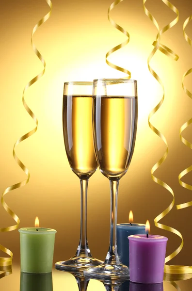 Pohár pezsgő, gyertyák és streamer, sárga háttér — Stock Fotó