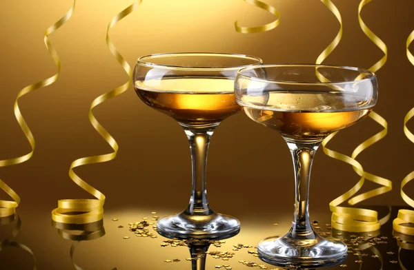 Glasses of champagne and streamer on yellow background — Stock Photo, Image
