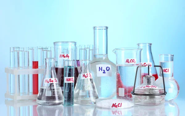 Reagenzgläser mit verschiedenen Säuren und Chemikalien auf blauem Hintergrund — Stockfoto