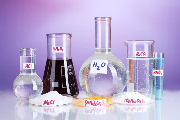 Probówki z różnych kwasów i środków chemicznych na fioletowym tle — Zdjęcie stockowe