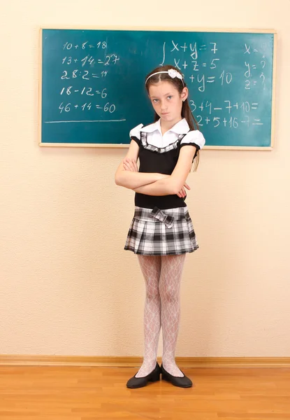 Linda menina no uniforme da escola na sala de aula — Fotografia de Stock