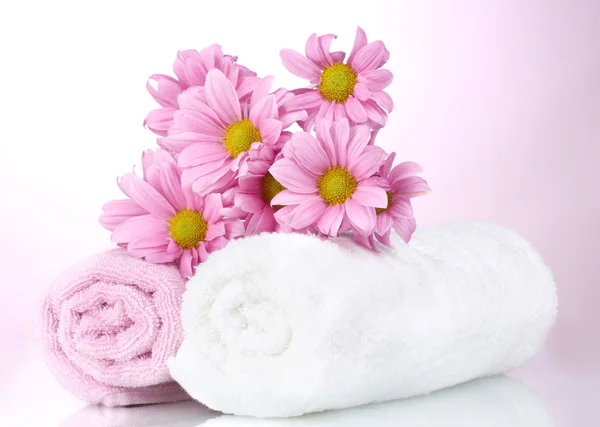 Törölköző és gyönyörű virágok rózsaszín háttér — Stock Fotó