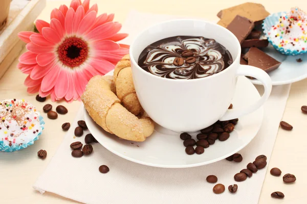 Cup of coffee and gerbera, beans, cinnamon sticks on wooden table — Stock Photo, Image