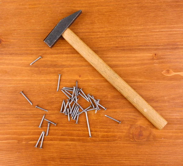 Hamer en metalen nagels op houten achtergrond — Stockfoto
