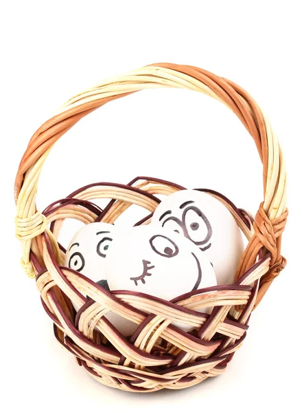 Bílá vejce s ksichty v košíku izolovaných na bílém — Stock fotografie