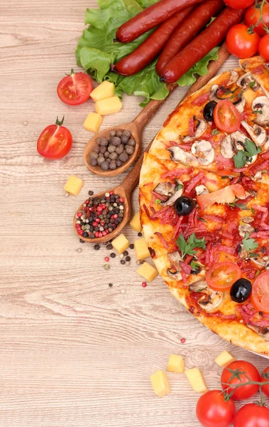Delicious pizza, vegetables and salami on wooden table — Stock Photo, Image