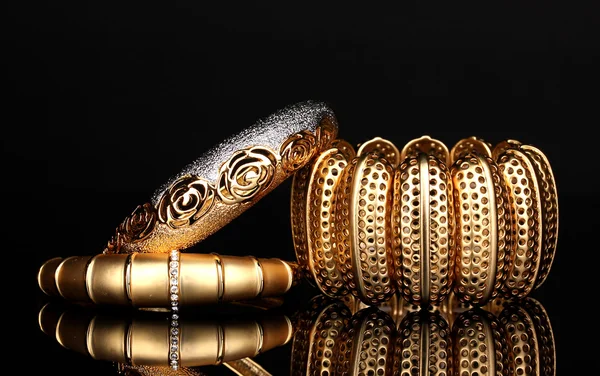 Красивые золотые браслеты изолированы на черном фоне — стоковое фото