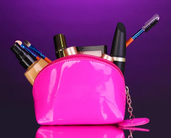 Make up bag con cosmetici e pennelli su sfondo viola — Foto Stock