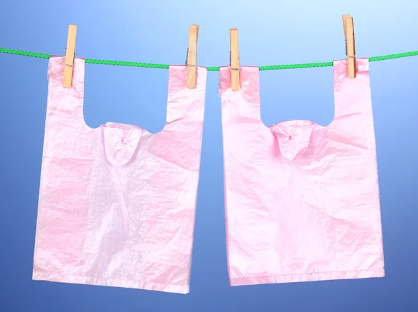 Cellophane bags hanging on rope on blue background — Stock Photo, Image