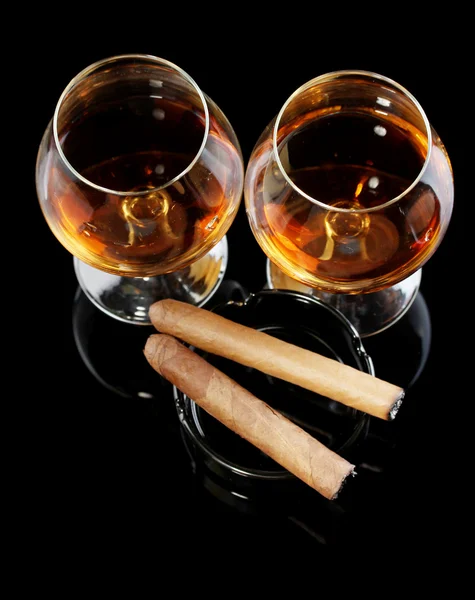 Deux verres de brandy et cigares sur fond noir — Photo