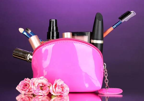 Maquiagem saco com cosméticos e escovas em fundo violeta — Fotografia de Stock