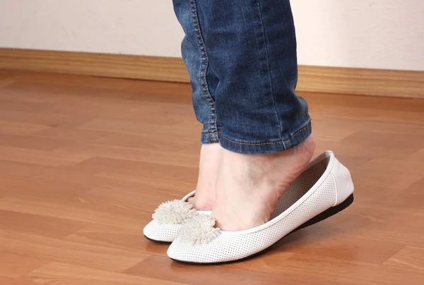 Ноги в джинсах и балетной обуви на деревянном фоне — стоковое фото