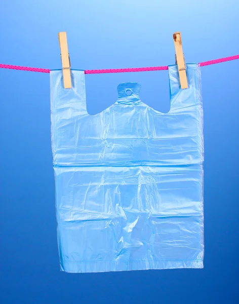 Saco de celofane pendurado na corda no fundo azul — Fotografia de Stock