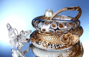 Beautiful silver and gold bracelets and ring on blue background clipart