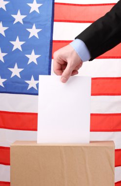 Hand with voting ballot and box on Flag of USA clipart