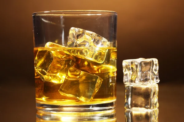 Vaso de whisky y hielo sobre fondo marrón — Foto de Stock
